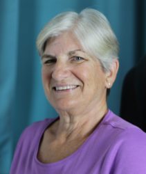 Photo of Dr. Kathy King, Purple shirt, white hair, blue eyes and a warm smile.